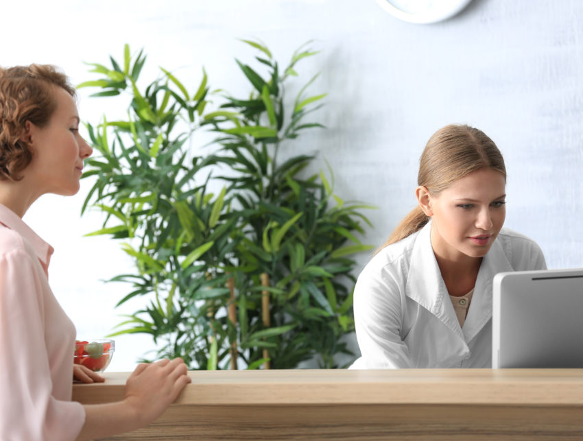 Young female receptionist with client in hospital Young female receptionist with client in hospital