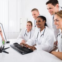 Doctors Videoconferencing On Computer Group Of Doctors Videoconferencing On Computer In Hospital